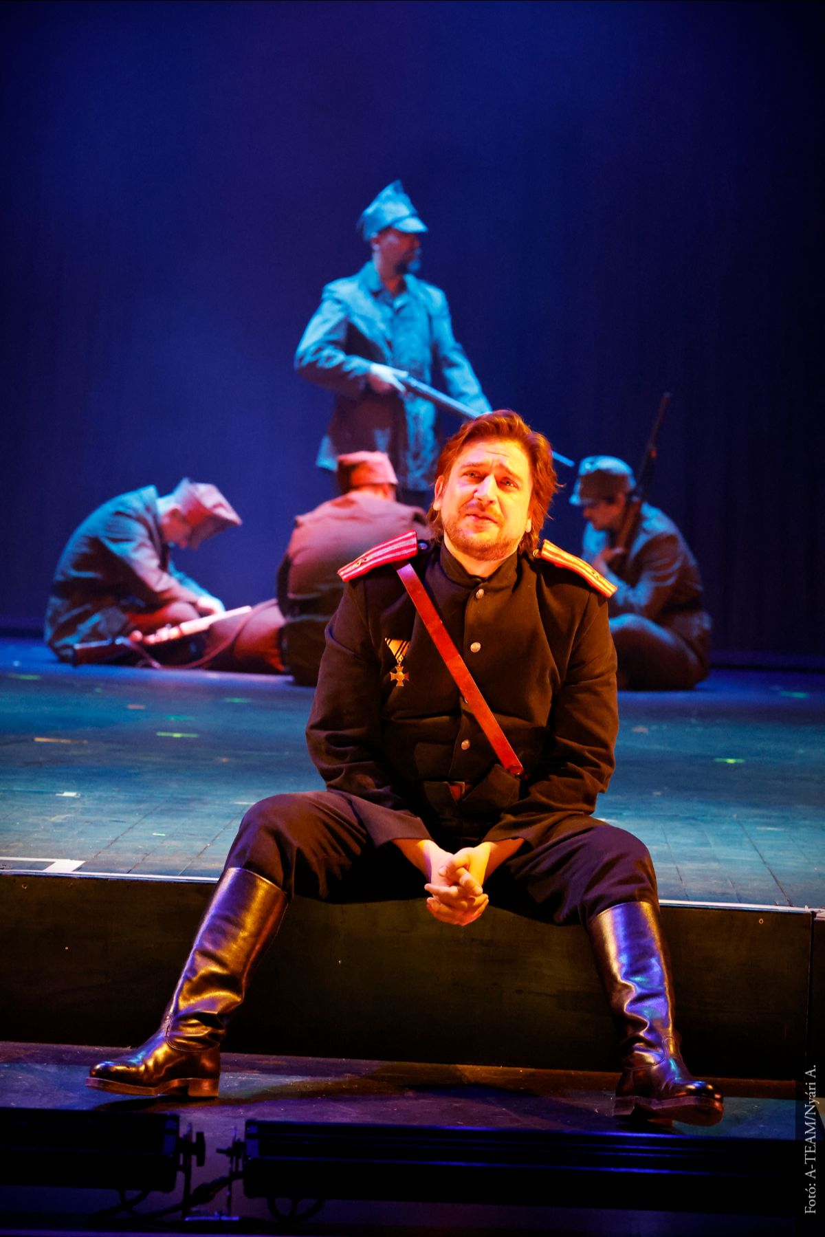 A színművész a Macbeth című darabban jelenet közben ül a színpad szélén a távolba nézve.