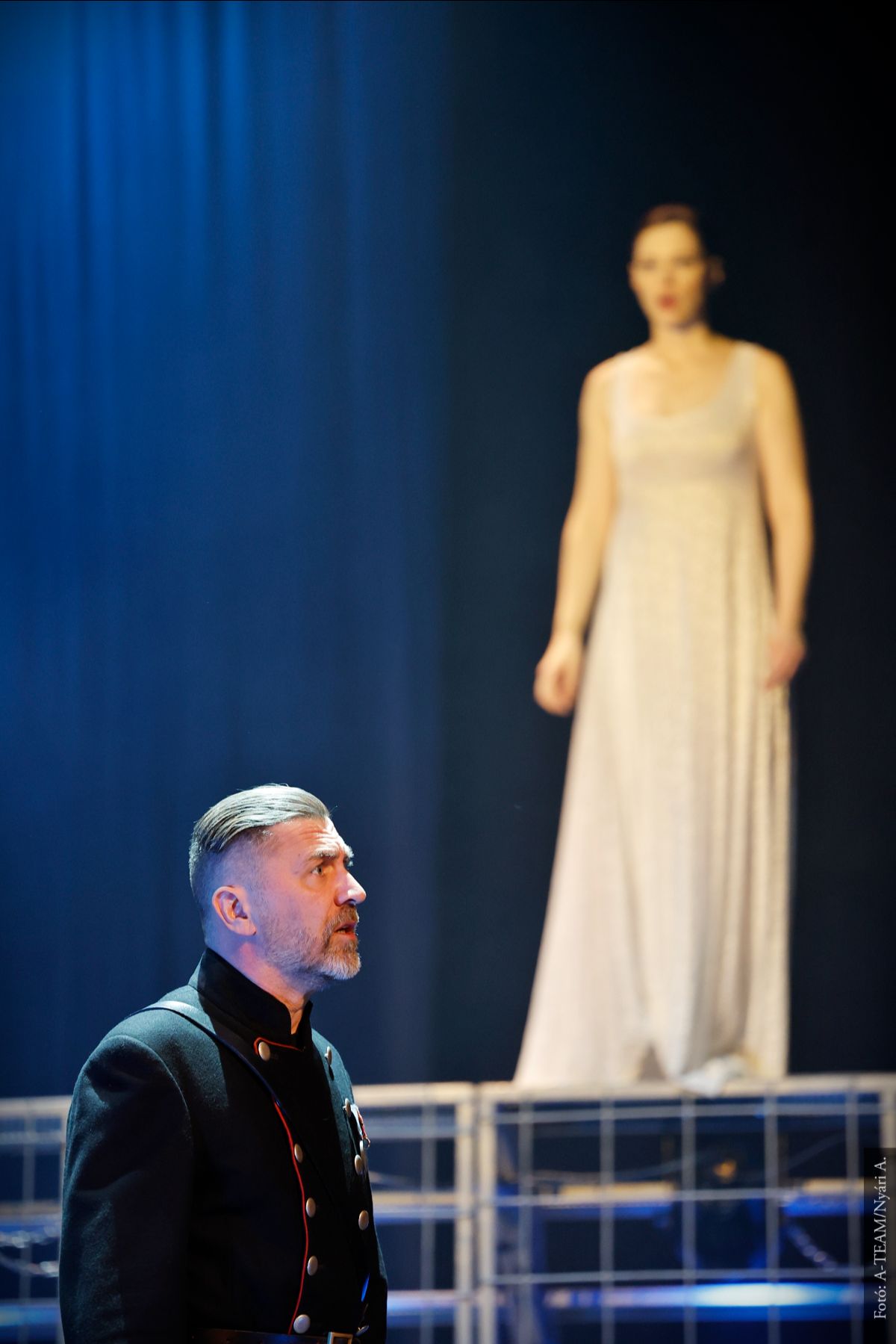 A színművész a Macbeth című darabban jelenet közben. Mögötte a háttérben partnernője nézni.